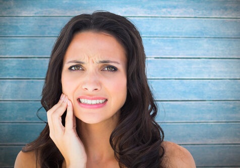 Pretty brunette with a toothache against wooden planks