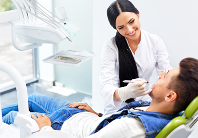 female-dentist-and-male-patient-having-his-teeth-examined female-dentist-and-male-patient-having-his-teeth-examined